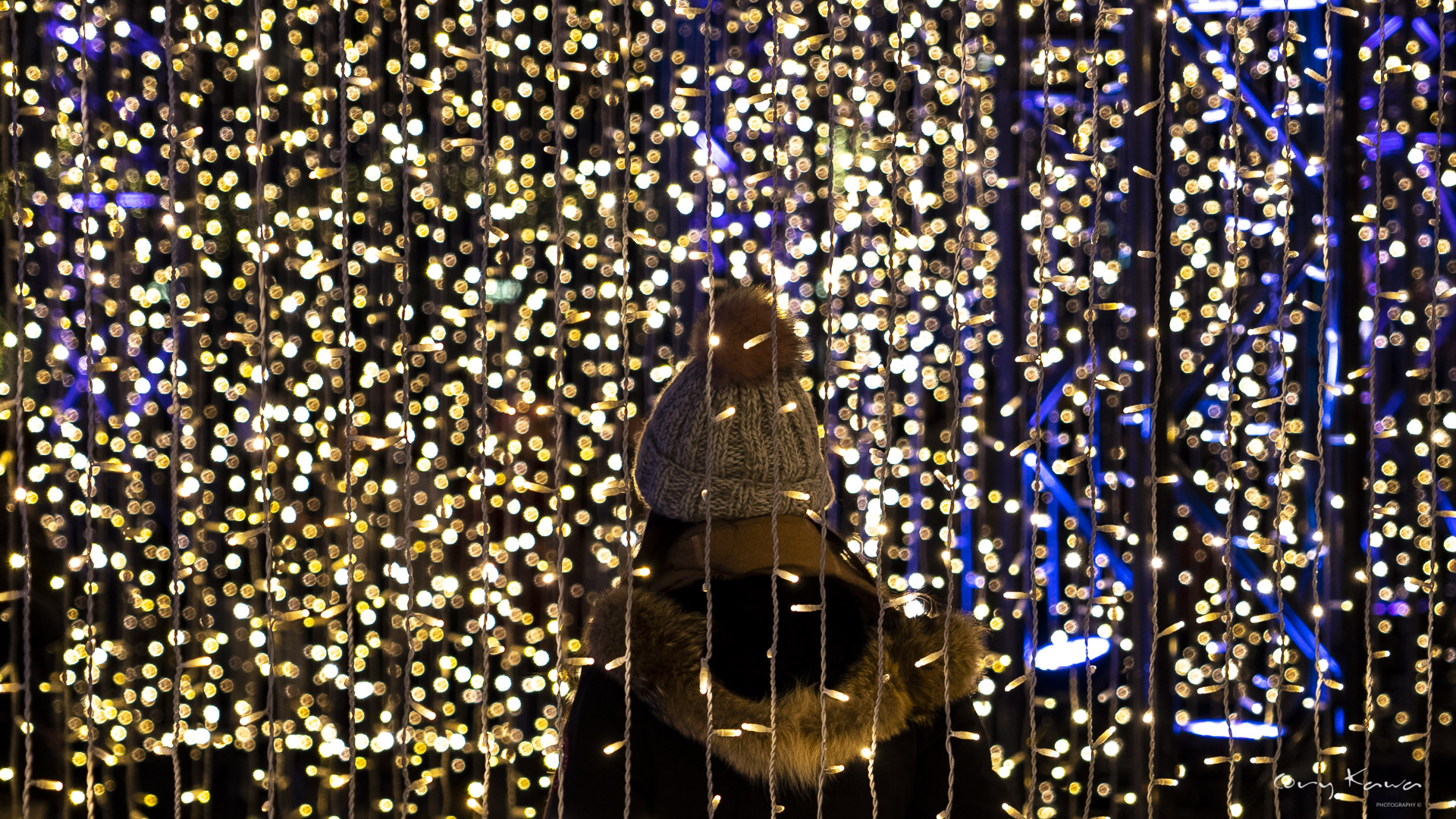The back of a lady surrounded by thousands of christmas lights