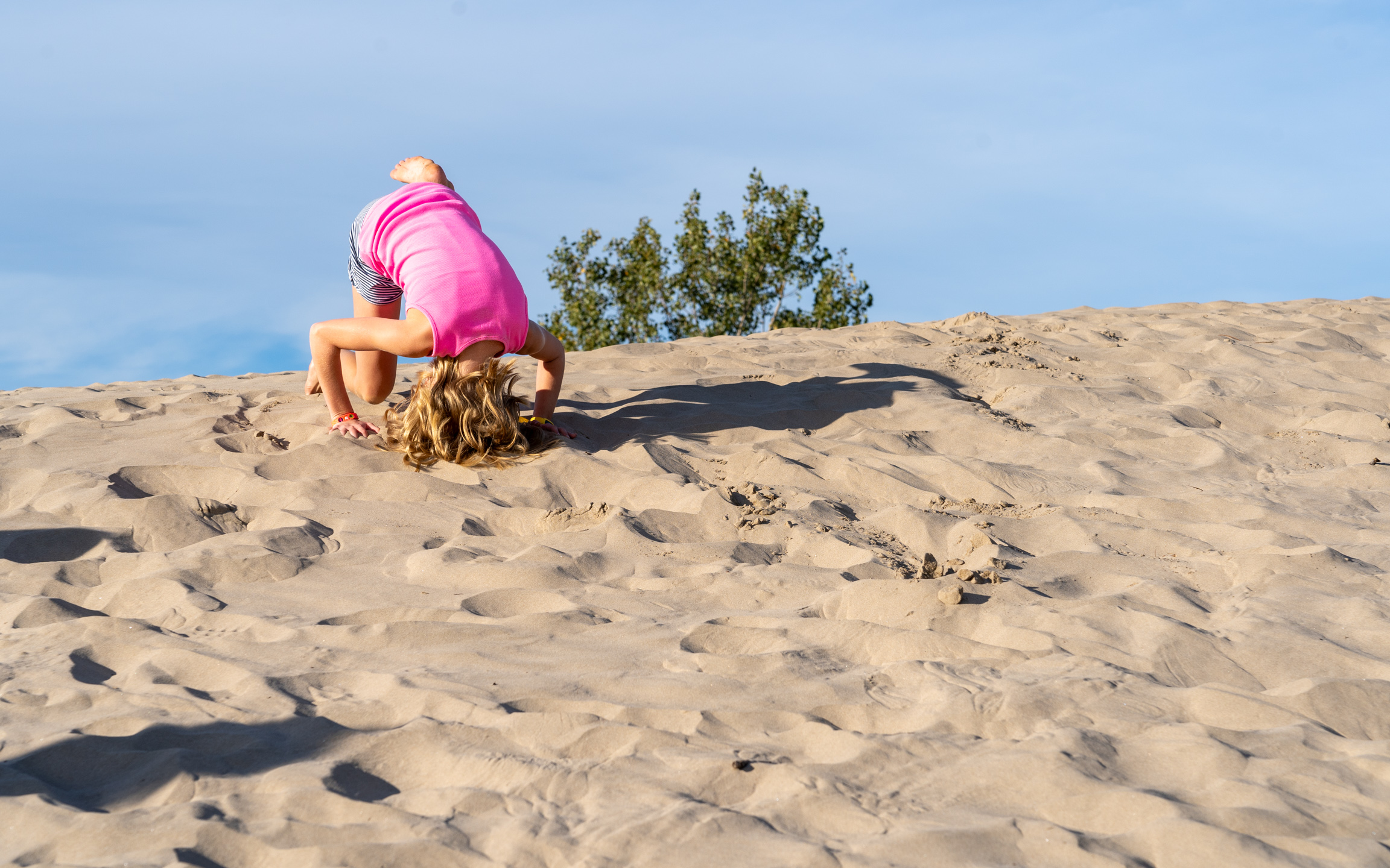 a girl going head over heals rolling down the dunes at sandbanks provincial park